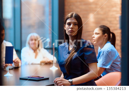 Medical professionals engage in discussion during a meeting at a modern healthcare facility in the early evening Medical professionals engage in discussion during a meeting at a modern healthcare facility in the early evening 135384213