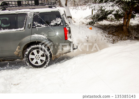 A car driving away in the snow, exhausting emissions 135385143