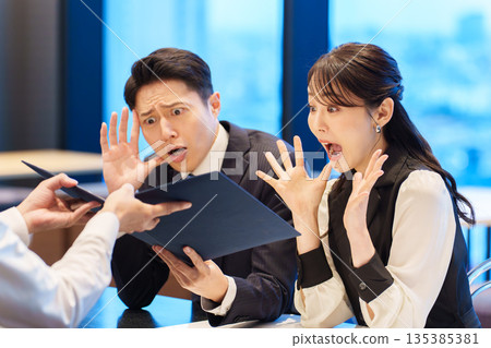 Surprised couple looking at a restaurant menu Surprised couple looking at a restaurant menu 135385381
