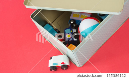 Multicolored toys in a metal box. Ambulance toy on the floor 135386112