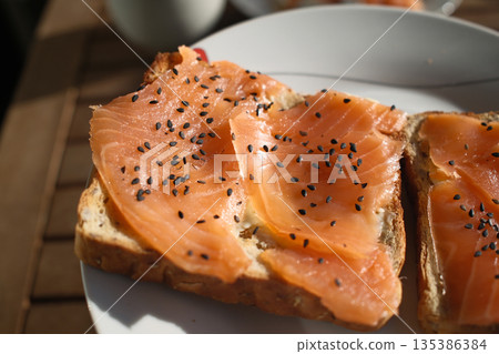 Gourmet salmon dish featuring smoked or raw cuts with toast or rice. 135386384