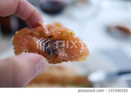 Gourmet salmon dish featuring smoked or raw cuts with toast or rice. 135386392