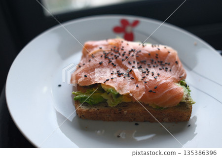 Gourmet salmon dish featuring smoked or raw cuts with toast or rice. 135386396