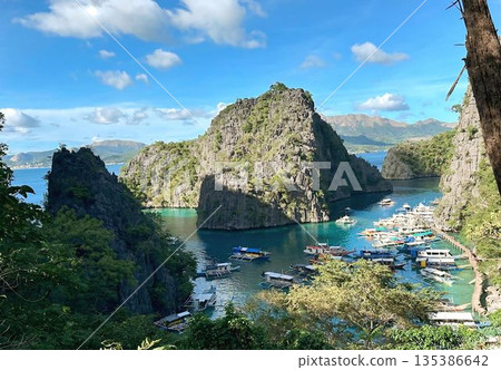 Panoramic view of Kayangan Lake with outrigger boats and limestone cliffs in Coron Panoramic view of Kayangan Lake with outrigger boats and limestone cliffs in Coron 135386642