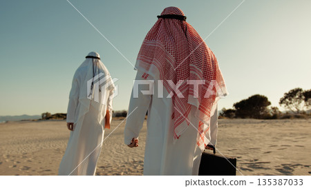 Sheiks Walking Away In The Desert With A Briefcase Sheiks Walking Away In The Desert With A Briefcase 135387033