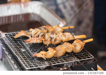小吃攤正在烹調烤魷魚 小吃攤正在烹調烤魷魚 135387199