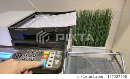 Close-Up of a Copier with Paper and Decorative Plant Close-Up of a Copier with Paper and Decorative Plant 135387896