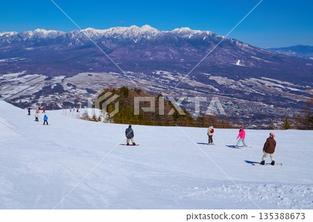 冬季，從長野縣富士見町富士見全景度假村纜車山頂站附近可以欣賞到八嶽山脈和滑雪者的全景。 135388673