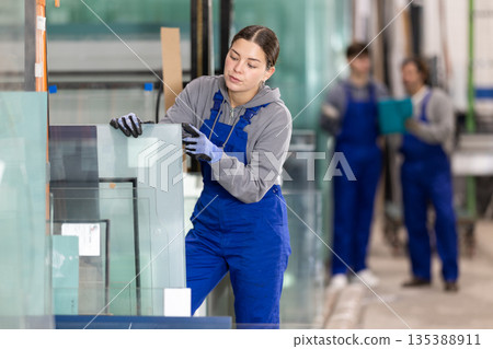 Young woman stacking glass sheets in factory Young woman stacking glass sheets in factory 135388911