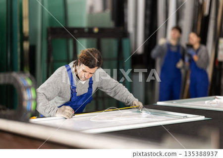 Adult man measuring sheet of glass in factory 135388937