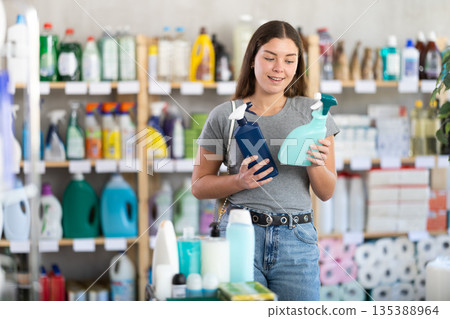 Young woman chooses cleaning spray in store Young woman chooses cleaning spray in store 135388964
