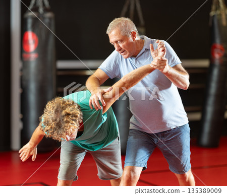 Focused senior man grappling in amateur wrestling session 135389009