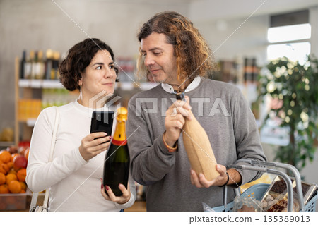 Husband and wife scanning champagne barcode Husband and wife scanning champagne barcode 135389013