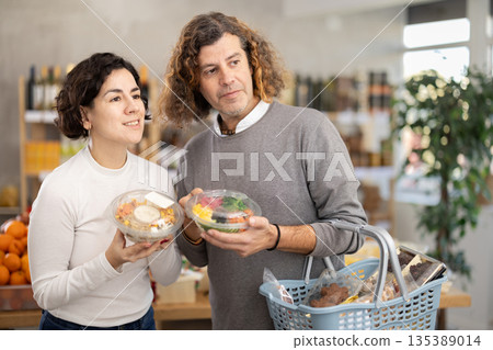 In store, spouses near counter are looking at poke salad In store, spouses near counter are looking at poke salad 135389014