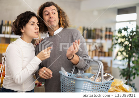 In store, couple looking for something on shelf of showcase In store, couple looking for something on shelf of showcase 135389021