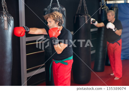 Strong man practicing punches on punching bag. Boxing training 135389074