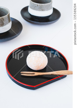 一組日式點心和茶,盛放在黑色托盤上。 一組日式點心和茶,盛放在黑色托盤上。 135389204