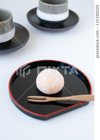 一組日式點心和茶,盛放在黑色托盤上。 一組日式點心和茶,盛放在黑色托盤上。 135389205