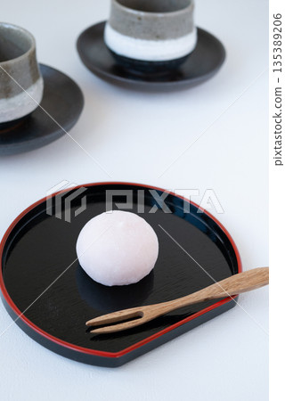 一組日式點心和茶,盛放在黑色托盤上。 一組日式點心和茶,盛放在黑色托盤上。 135389206