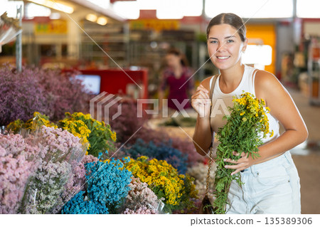 Young girl holding bouquet of dry flowers in large plants market Young girl holding bouquet of dry flowers in large plants market 135389306