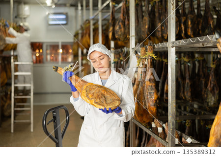 Girl employee checks jamon. Quality control Girl employee checks jamon. Quality control 135389312
