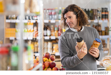 Adult man chooses beans at grocery store 135389337