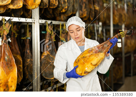 female worker checks the quality of jamon in a factory female worker checks the quality of jamon in a factory 135389380