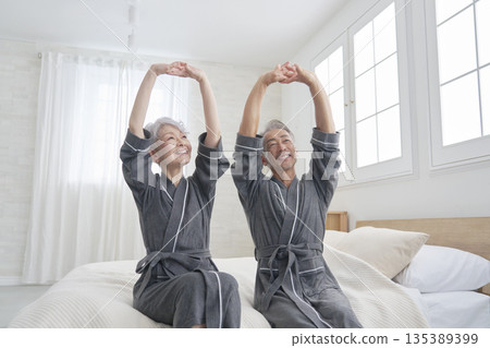Senior couple stretching in the bedroom Senior couple stretching in the bedroom 135389399