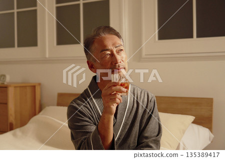 Senior man drinking whiskey in his bedroom Senior man drinking whiskey in his bedroom 135389417