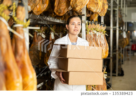 In hamon factory department, girl worker carries cardboard boxes 135389423
