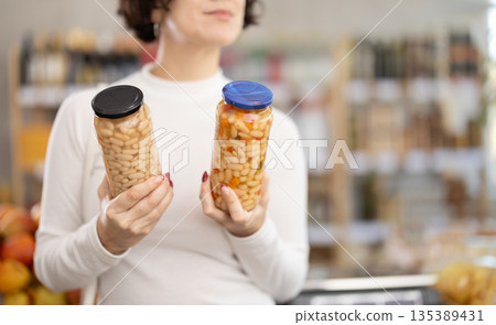 In store, customers near counter are looking at canned beans 135389431