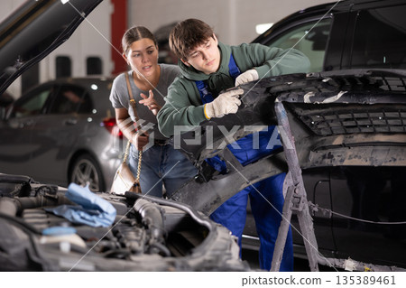Mechanic consulting woman on car bumper repair 135389461