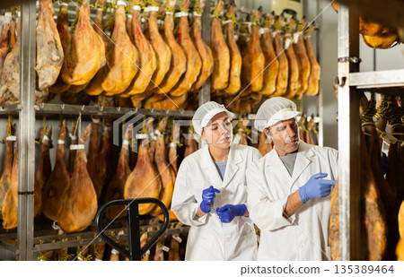 Man and girl worker check jamon, talk and discuss result 135389464