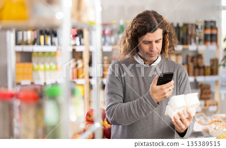 Adult man scanning qr code for yogurt Adult man scanning qr code for yogurt 135389515