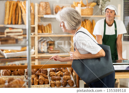 European senior woman look at rack shelf showcase filled with various flour products European senior woman look at rack shelf showcase filled with various flour products 135389518