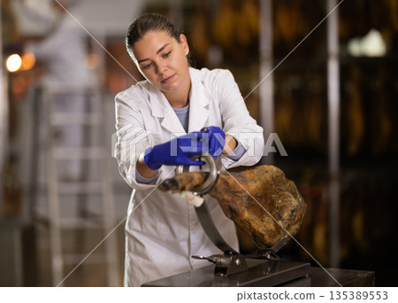 Girl factory worker places hamon in cutting device jamonero 135389553
