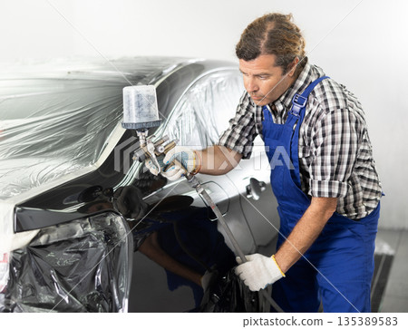 Experienced auto painter working in car repair workshop Experienced auto painter working in car repair workshop 135389583