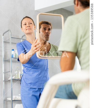 Adult man examining his face after cosmetic procedure 135389588