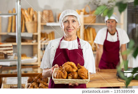 Elderly woman seller with croissants in basket Elderly woman seller with croissants in basket 135389590