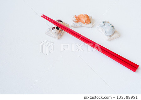 Red chopsticks and cute cat chopstick rest on white background 135389951
