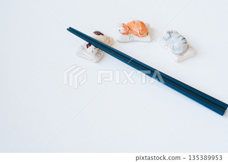 Blue chopsticks and cute cat chopstick rest on white background 135389953