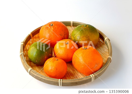 Ripe and unripe mandarins served on a colander on a white background Ripe and unripe mandarins served on a colander on a white background 135390006