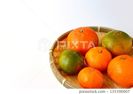 盛放在白色背景上的漏勺裡的成熟和未成熟的柑橘 盛放在白色背景上的漏勺裡的成熟和未成熟的柑橘 135390007