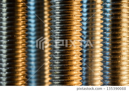 A repetitive pattern of vertical screw threads illuminated by warm golden light A repetitive pattern of vertical screw threads illuminated by warm golden light 135390088