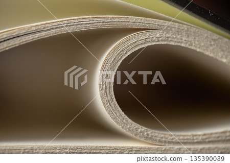 Extreme close up of white paper pages curving into a spiral with soft natural light and shadows 135390089