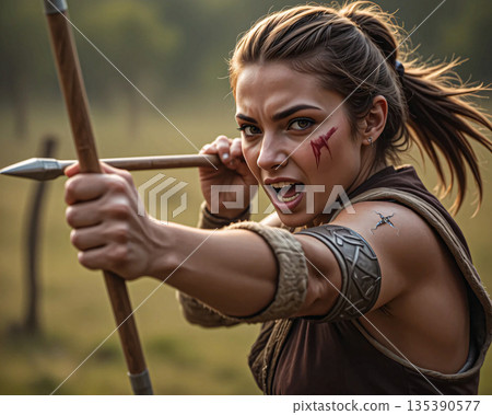 Fierce female warrior holding spears. Young female warrior gripping a spear poised to throw, exuding intensity. Her brown hair is pulled back into a ponytail.  135390577