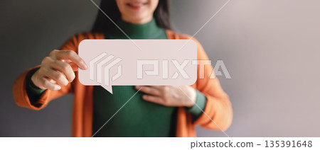 Smiling Woman holding blank Bubble Speech. Symbol of free speech, empowerment 135391648