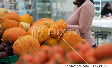 Woman choosing pumpkin in a supermarket produce section, shopping and healthy food lifestyle 135391808