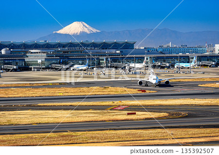 一架飛機從羽田機場起飛，遠處是白雪皚皚的富士山。 135392507