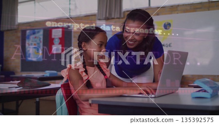 Leaning teacher and student collaborating on laptop in classroom, with pencil case and textbooks 135392575